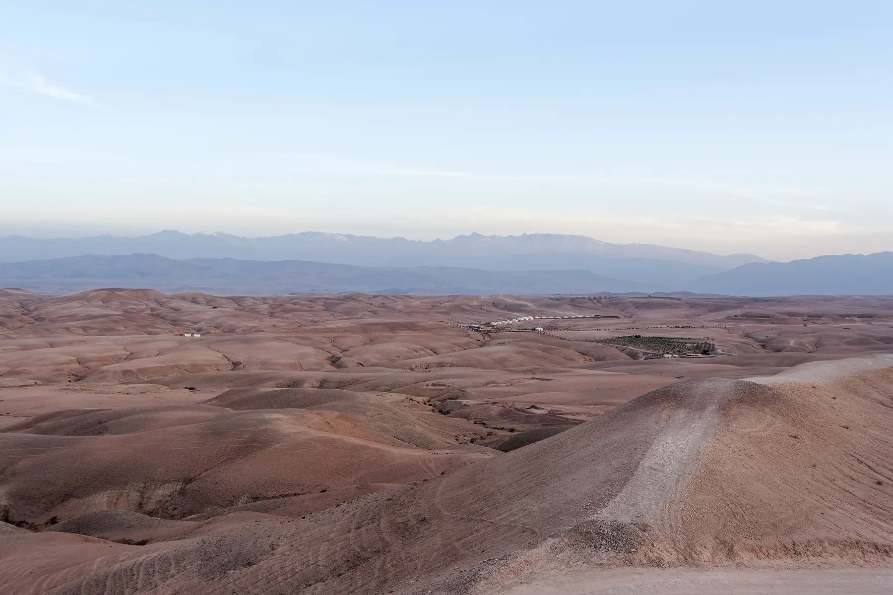 Bare stone hills of the Agafay Desert, with mountains in the background