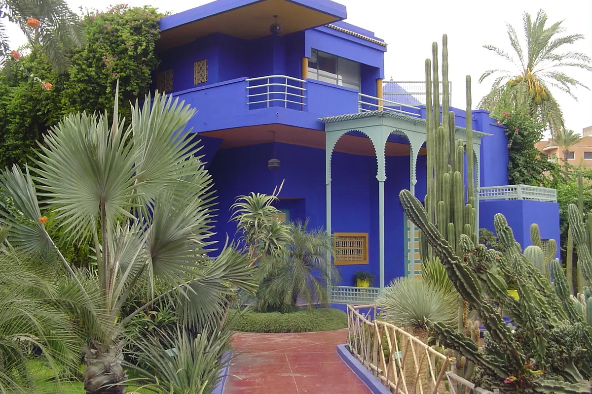 Blue building of the Jardin Majorelle surrounded by cacti and palm trees